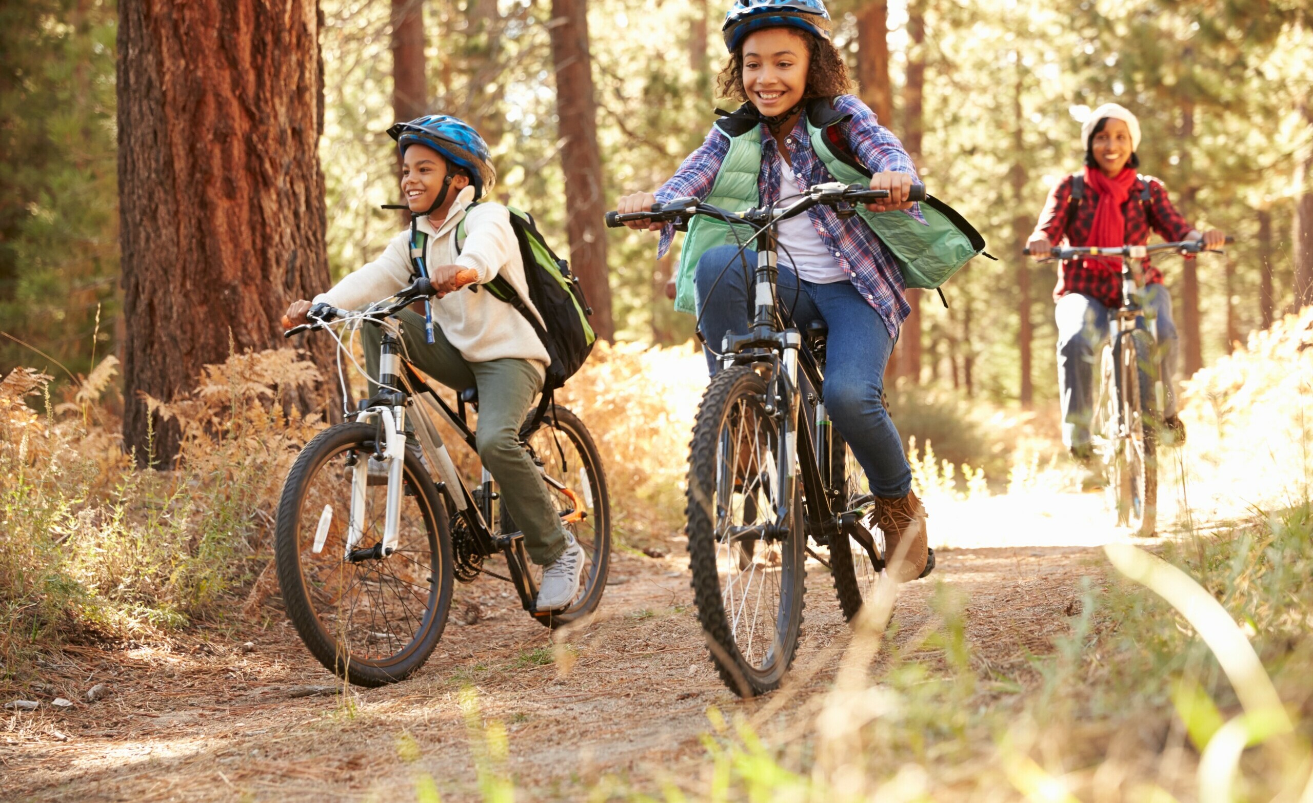 Grandparents With Children Cycling Through Fall Woodland